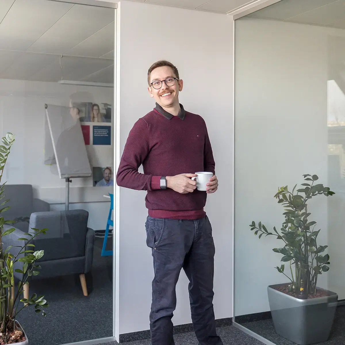 Senior System Engineer von SmartIT im ganzkörper Portrait steht im Büro und lächelt in die Kamera
