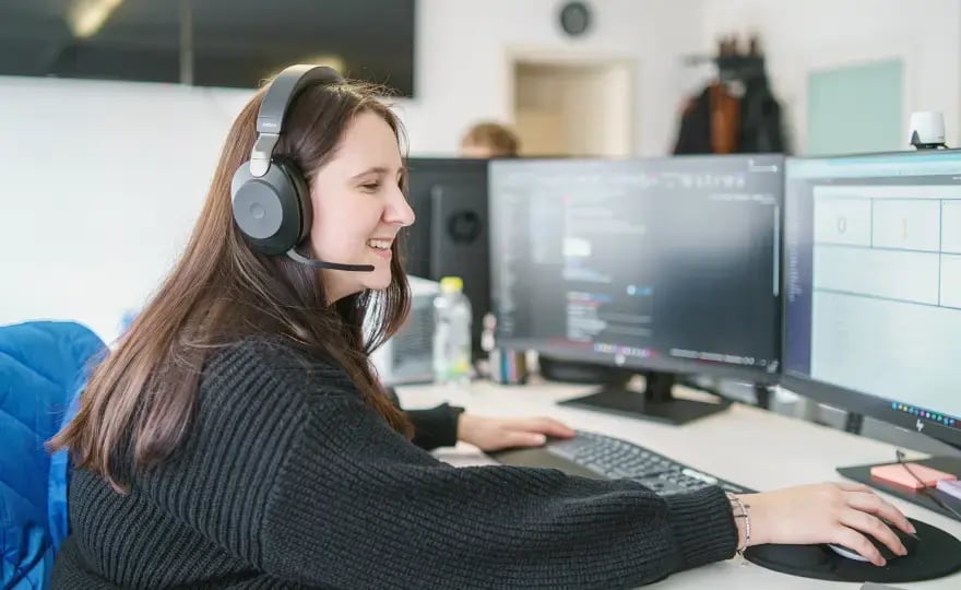 SmartIT-SmartWorkplace-Anwendersupport. Person mit Headset an einem Schreibtisch