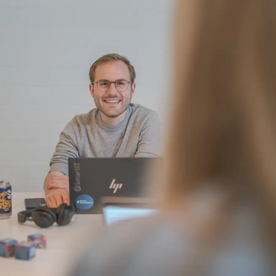 SmartiT Mitarbeitenderlächelt unscharf von hinten erkennbare Person bei einem Bewerbungsgespräch an