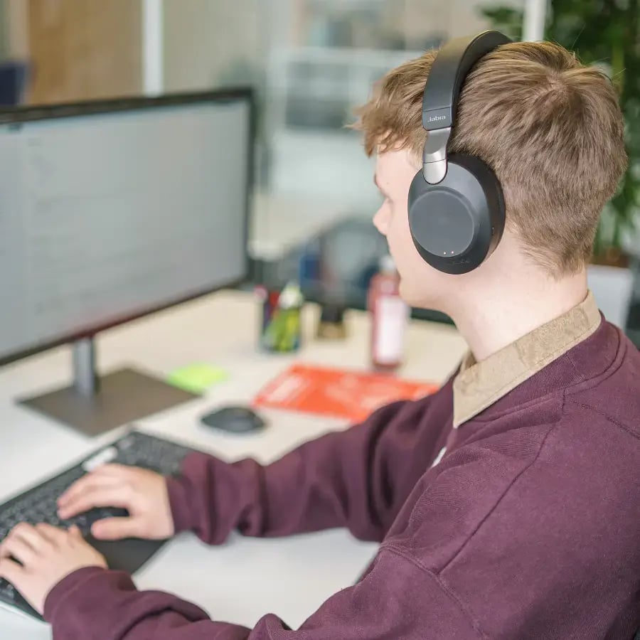 SmartIT Mitarbeitender leicht von hinten fotografiert, trägt Kopfhörer und arbeitet