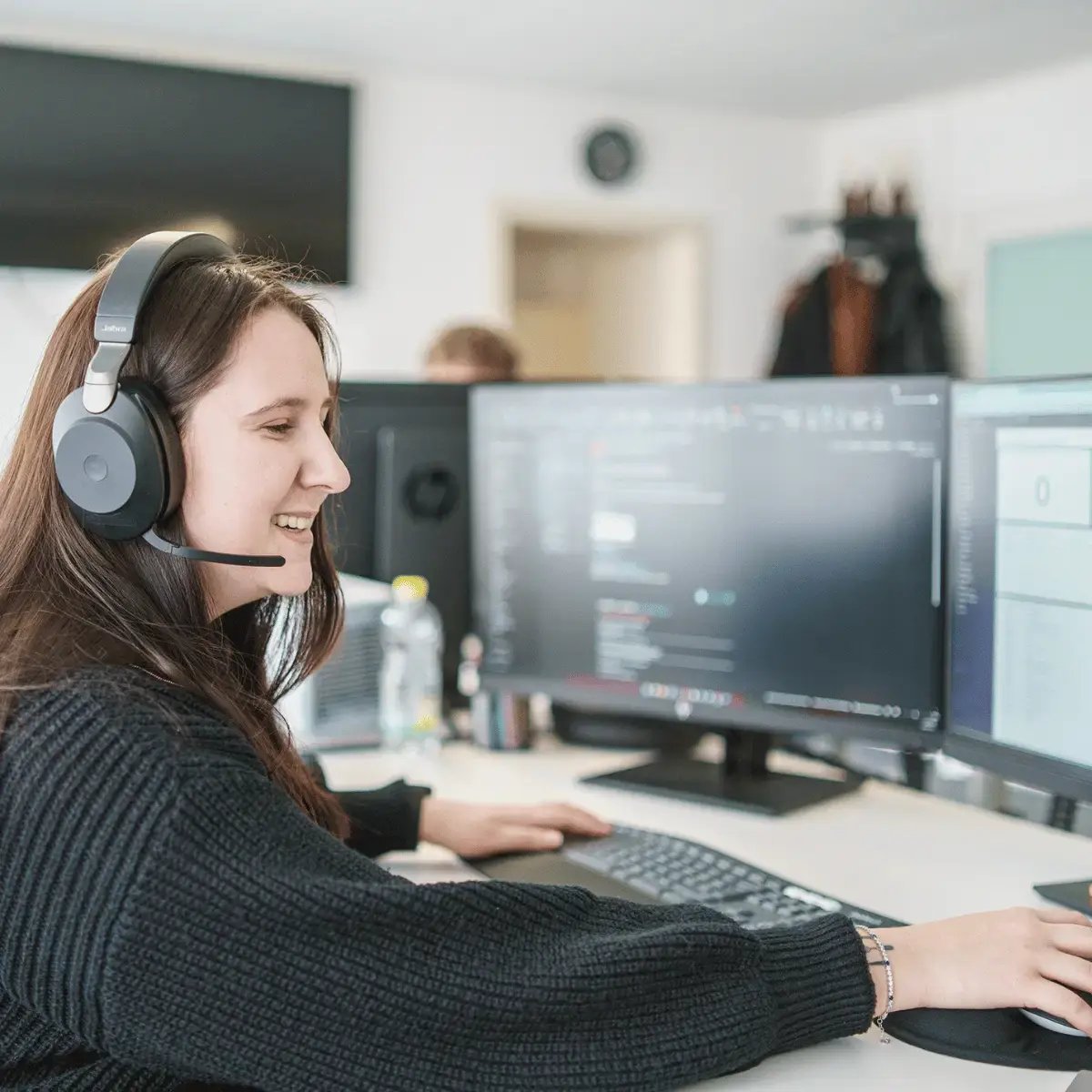 SmartIT-SmartWorkplace-Anwendersupport. Person mit Headset an einem Schreibtisch